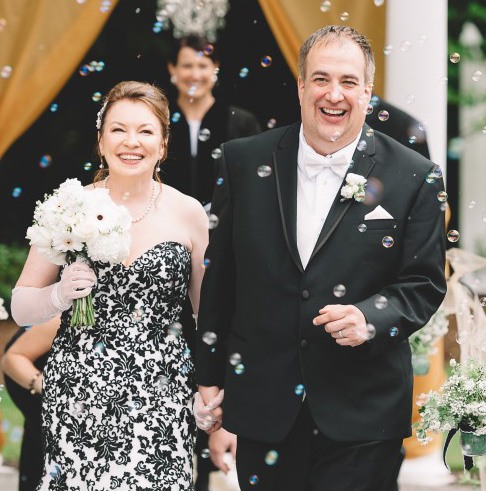 爱你的新娘成功的故事，穿着一件黑色蕾丝礼服拿着与她的新郎的白花